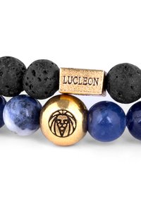 Armband aus Lavastein und blauen Perlen, verziert mit einer goldenen Akzentperle mit einem Löwenemblem und einem Metallanhänger, der "LUCLEON" eingestanzt ist.