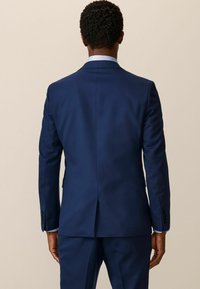 Marineblauer Anzug mit taillierter Passform, einem hinteren Schlitz, Reverskragen und knöpfbaren Manschetten. Glatter Stoff mit strukturierter Silhouette.