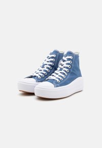 Baskets montantes en toile bleu clair avec des lacets blancs, bout en caoutchouc et semelle épaisse blanche. Agrémentées de détails de couture.