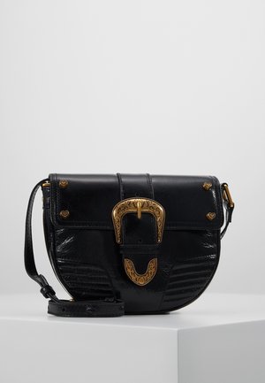 Czarna skórzana torba na ramię w kształcie półksiężyca z grawerowaną złotą klamrą i ćwiekami w kształcie serc na klapie, prezentowana na białym postumencie.