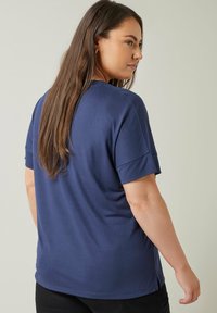 Mörkblå t-shirt med kort ärm och rund halsringning, jämn tygkvalitet, avslappnad passform och sidslitsar vid fållkanten.