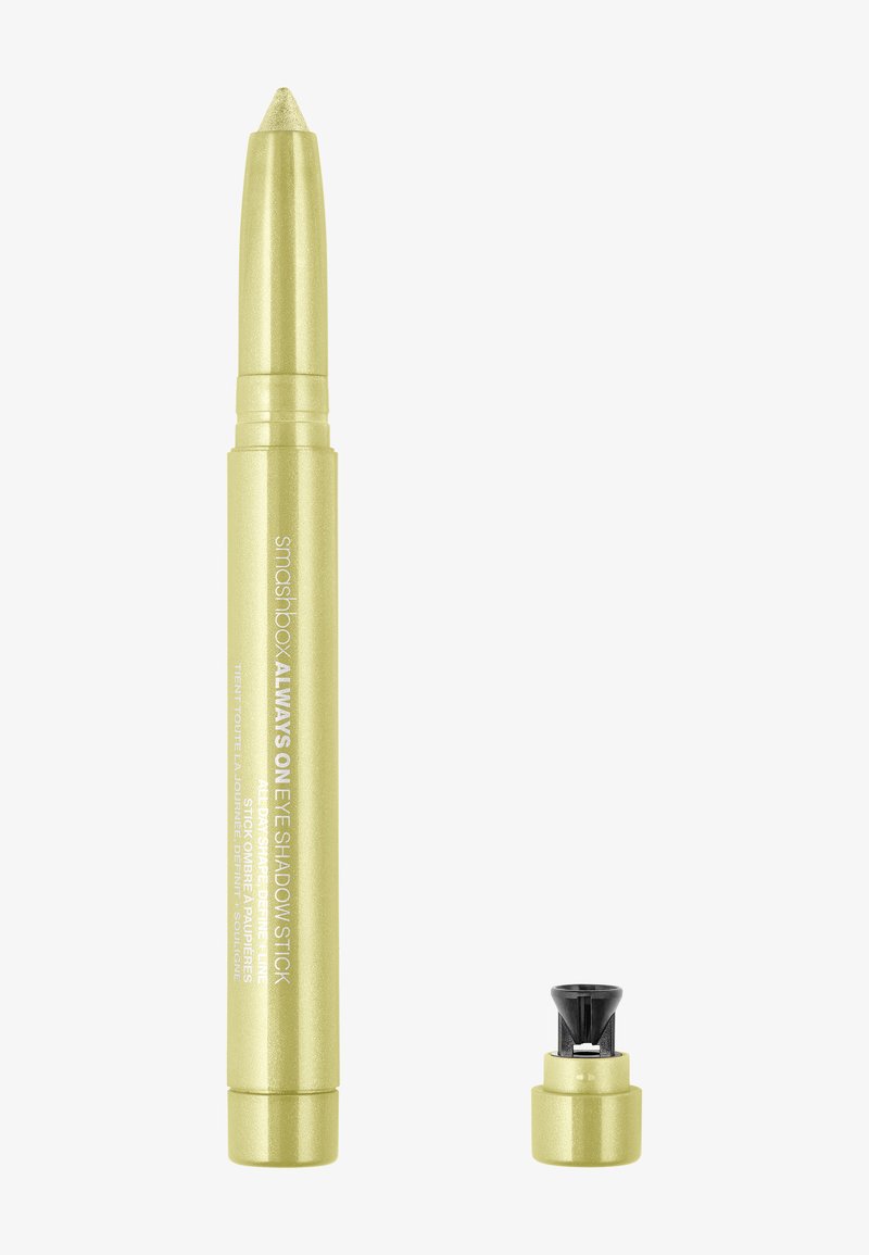 Crayon ombre à paupières jaune avec une pointe effilée et un capuchon noir amovible. Du texte imprimé sur le côté indique le nom du produit et les instructions.