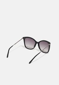 Ochelari de soare din plastic negru, cu formă de ochi de pisică, lentile cu gradient și accente din metal argintiu pe temples. Textură netedă și design elegant.