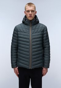 Giubbotto imbottito di colore verde scuro con trapuntatura a zigzag, chiusura con zip e cappuccio regolabile. Presenta una texture liscia e un design minimalista.