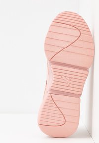 Semelle de chaussure de sport Puma en rose tendre, avec un relief texturé pour une meilleure adhérence, un logo central et une finition en caoutchouc lisse.