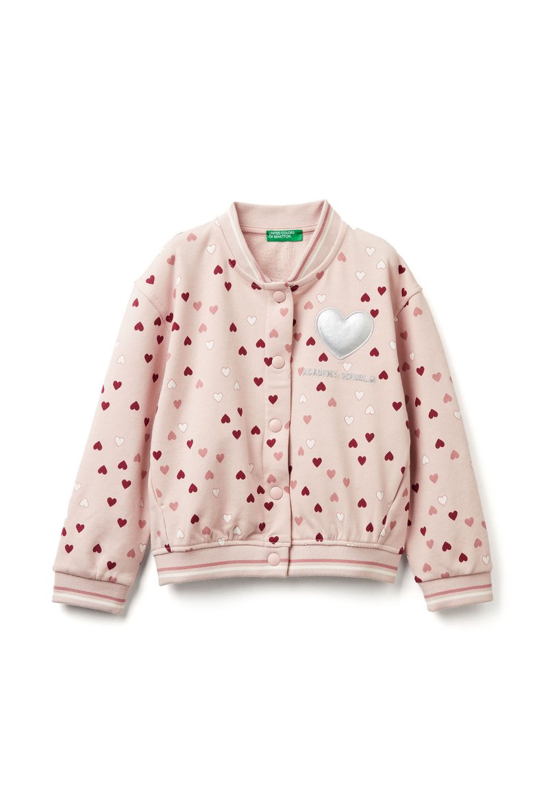Světle růžová bomber bunda s rozptýlenými červenými a bílými srdci, stříbrným srdcovým akcentem na prsou a žebrovanými manžetami s pruhovanými detaily.