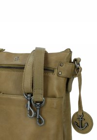 Borsa in pelle verde oliva con tracolla regolabile, chiusura con zip e due ganci metallici. Presenta un charm a forma di ancora e cuciture decorative.