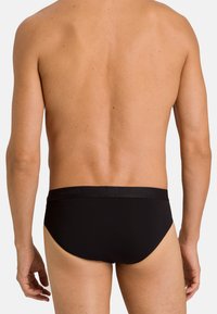 Zwarte katoenen slip met elastische tailleband met het merklogo; gladde textuur en aansluitende pasvorm, ontworpen voor comfort en ondersteuning.