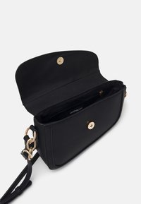 Borsa a tracolla nera in texture con hardware dorato, con pattina aperta che mostra il scomparto con zip interno e tracolla regolabile.