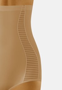 Hochgeschnittene Formungsunterwäsche in Nude-Farbe, gefertigt aus glattem Stoff mit transparenten Streifenpaneelen an den Seiten für zusätzlichen Textur- und Designdetails.