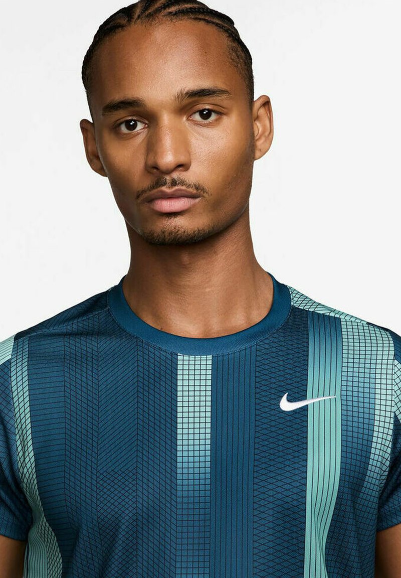 Short-sleeve Nike t-shirt in dark blue and teal, featuring geometric patterns, a crew neck, and a small white Nike logo on the chest.