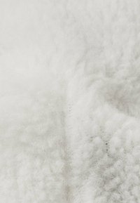 Weißer Stoff mit einer weichen, flauschigen Textur, der eine faserige Erscheinung aufweist, mit sichtbaren Fasern und einem leicht melierten Muster.