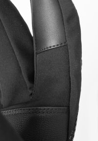Gants noirs présentant une combinaison de cuir texturé et de tissu lisse, avec des coutures visibles et une forme structurée.