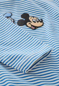 Pásikovaná modro-biela látka s vyšívaným motívom Mickey Mouse. Textúra je jemná, s horizontálnymi pruhmi a hladkým povrchom.