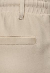 Beige sweatpants met een zachte textuur, elastische tailleband en een vierkante, gestikte zakdetail aan de achterkant.