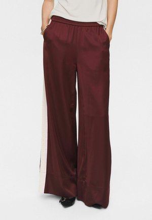 Burgundy satin wide-leg pants with an elastic waistband and side pockets, featuring a contrasting light-colored side panel detail.