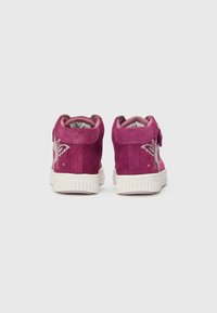 Rosa semskede høyhælte sneakers med hvit gummisåle, med et sommerfugldesign på yttersiden og borrelåsstropp for lukking.