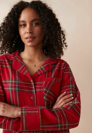 Röd rutig knapp-up pyjamas med långa ärmar, utrustad med en bröstficka och kontrasterande gröna och gula linjer i mönstret.