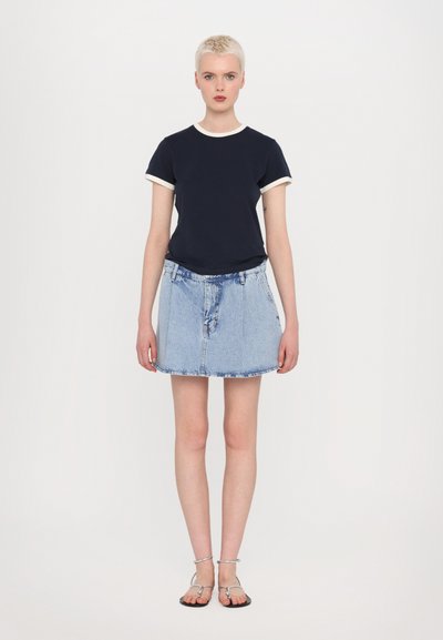 Navy t-shirt with white trim, paired with a light blue denim skirt. Model wears silver sandals. Simple, casual outfit with a relaxed fit.