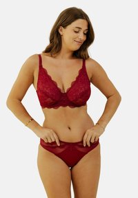 Soutien-gorge en dentelle rouge et ensemble de culotte assorti avec des motifs floraux, des bords festonnés, et un matériel décoratif au centre avant.