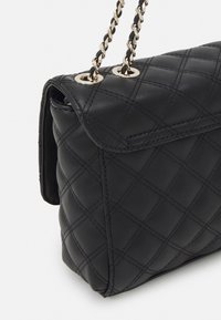 Borsa a tracolla in pelle nera trapuntata con chiusura a pattina, dotata di tracolla in catena dorata e motivo a diamante cucito. Texture liscia e finitura lucida.