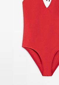 Maillot de bain une pièce rouge avec un décolleté en V profond et des bretelles fines, présenté à plat sur fond blanc.
