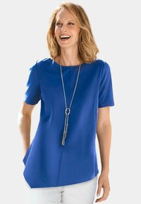 Blauw kortmouwtop met een rechte snit, voorzien van een ronde halslijn en zijzakken, gecombineerd met een lange zilveren ketting.