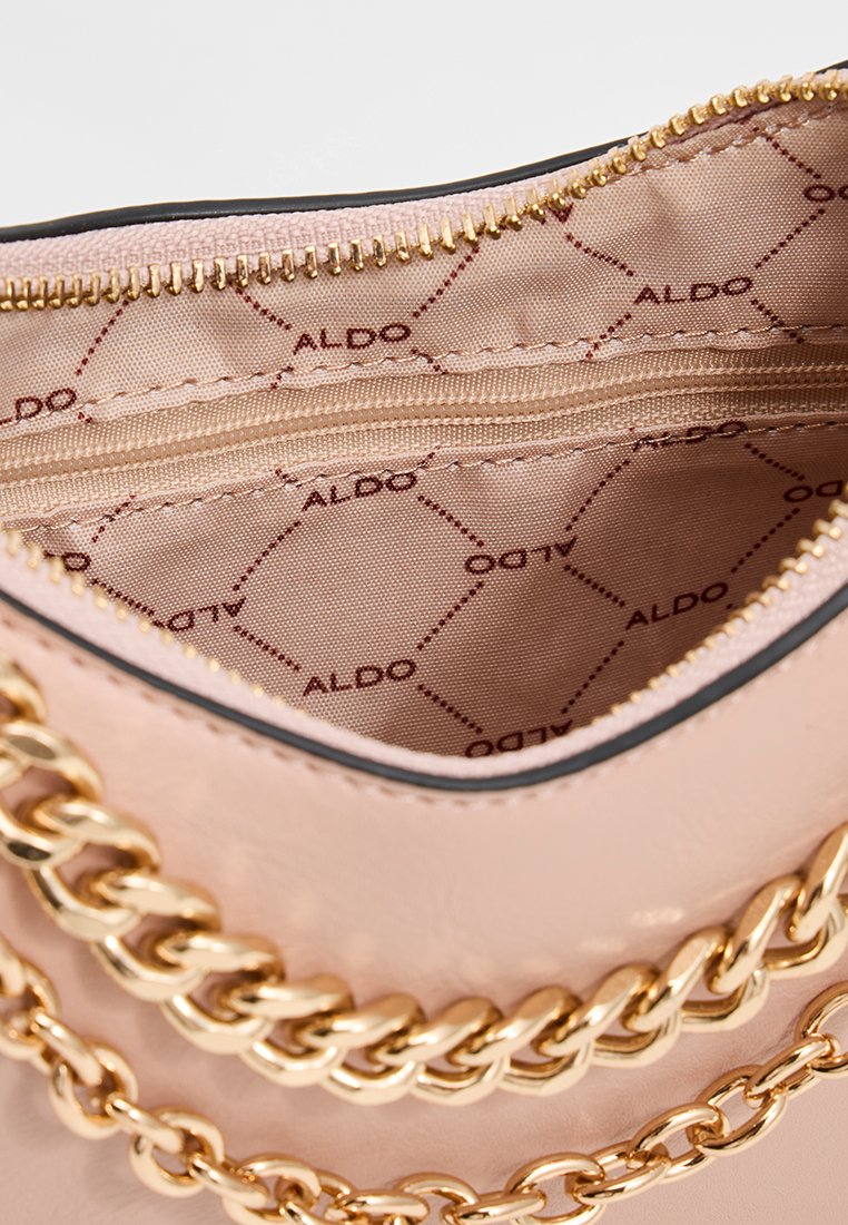 Sac à main rose clair avec des détails en chaîne dorée. L'intérieur comprend une section zippée et un tissu à motif avec le branding "ALDO". Texture extérieure lisse.
