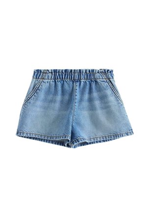 Junges Mädchen trägt ein pinkes "icy besties" T-Shirt, Jeans-Shorts, blauen Bucket-Hut und beige Flip-Flops, steht und lächelt vor weißem Hintergrund.