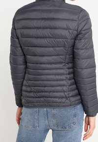 Chaqueta acolchada gris oscuro con diseño acolchado de costuras horizontales, cuello alto y ajuste ceñido. Tela ligera y brillante.