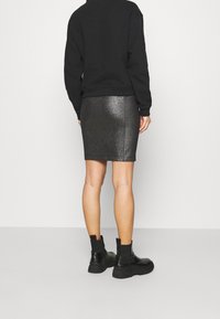 Black sweatshirt with a relaxed fit paired with a black, metallic shimmer pencil skirt. Black ankle boots complete the look.