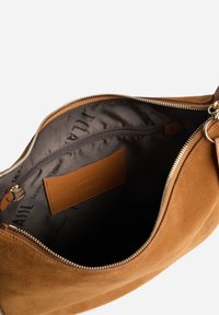 Borsa in camoscio marrone con chiusura a zip, dotata di fodera interna nera e tasca interna con zip. Dettagli in metallo color oro lungo la cerniera.