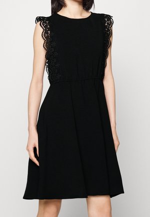 Robe noire sans manches avec des détails en dentelle florale sur les épaules et les côtés, taille ajustée et jupe évasée longueur genou.