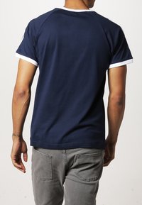 Námořnická modrá tričko s bílým lemem na límci a rukávech, volný střih, vyrobené z měkké bavlny, s hladkým texturovaným povrchem.