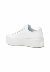 Zapatillas de plataforma blancas de lona con punta redondeada, ojales plateados, suela texturizada y una pestaña trasera etiquetada con el nombre de la marca.
