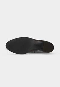Semelle de chaussure habillée noire avec grip avant texturé, milieu lisse, petit talon empilé et marquage de taille 41 1/2 visible.