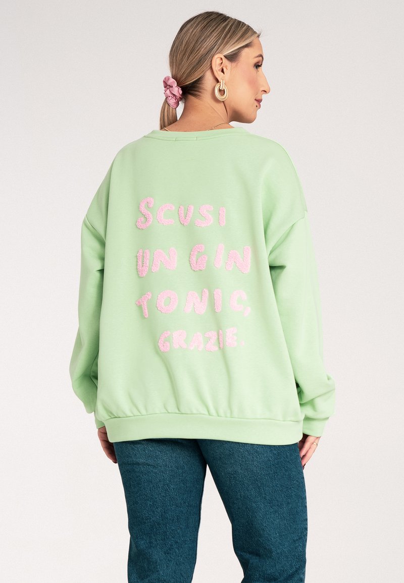 Miętowa, oversize'owa bluza z różowym, puszystym napisem "SCUSI UN GIN TONIC, GRAZIE" z tyłu. Miękki materiał, luźny krój.