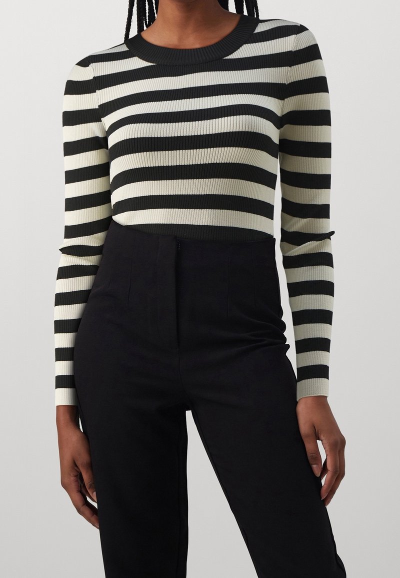 Czarny i kremowy pasek, prążkowany top z długim rękawem i okrągłym dekoltem, zestawiony z czarnymi spodniami o wysokim stanie. Teksturowany materiał dla dopasowanego wyglądu.
