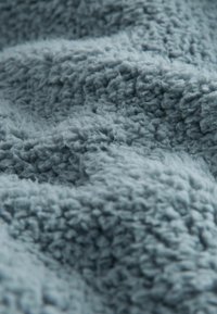 Faux fur blanket in light blue. Soft, textured surface with a plush, fluffy appearance, featuring irregular patterns and a cozy look.