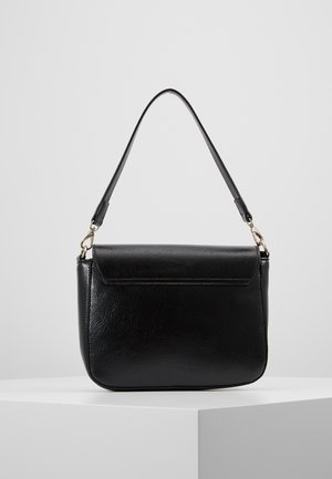 Musta teksturoidusta nahasta valmistettu olkalaukku, jossa on läppäkiinnitys ja säädettävä hihna, esillä valkoisella jalustalla harmaata taustaa vasten.