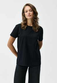 Czarna bawełniana koszulka z krótkim rękawem, z delikatnym wzorem z małych, błyszczących akcentów z przodu. Klasyczny krój z okrągłym dekoltem.