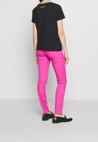 Černé bavlněné tričko s krátkým rukávem, spárované s růžovými úzkými džíny a černými botami. Tento outfit má jednoduchý design bez vzorů.