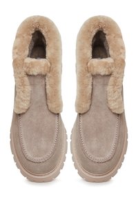 Chaussures à enfiler en suede marron clair avec un doublure en fourrure beige, bout arrondi, couture contrastante et semelle en caoutchouc texturé pour une meilleure adhérence.
