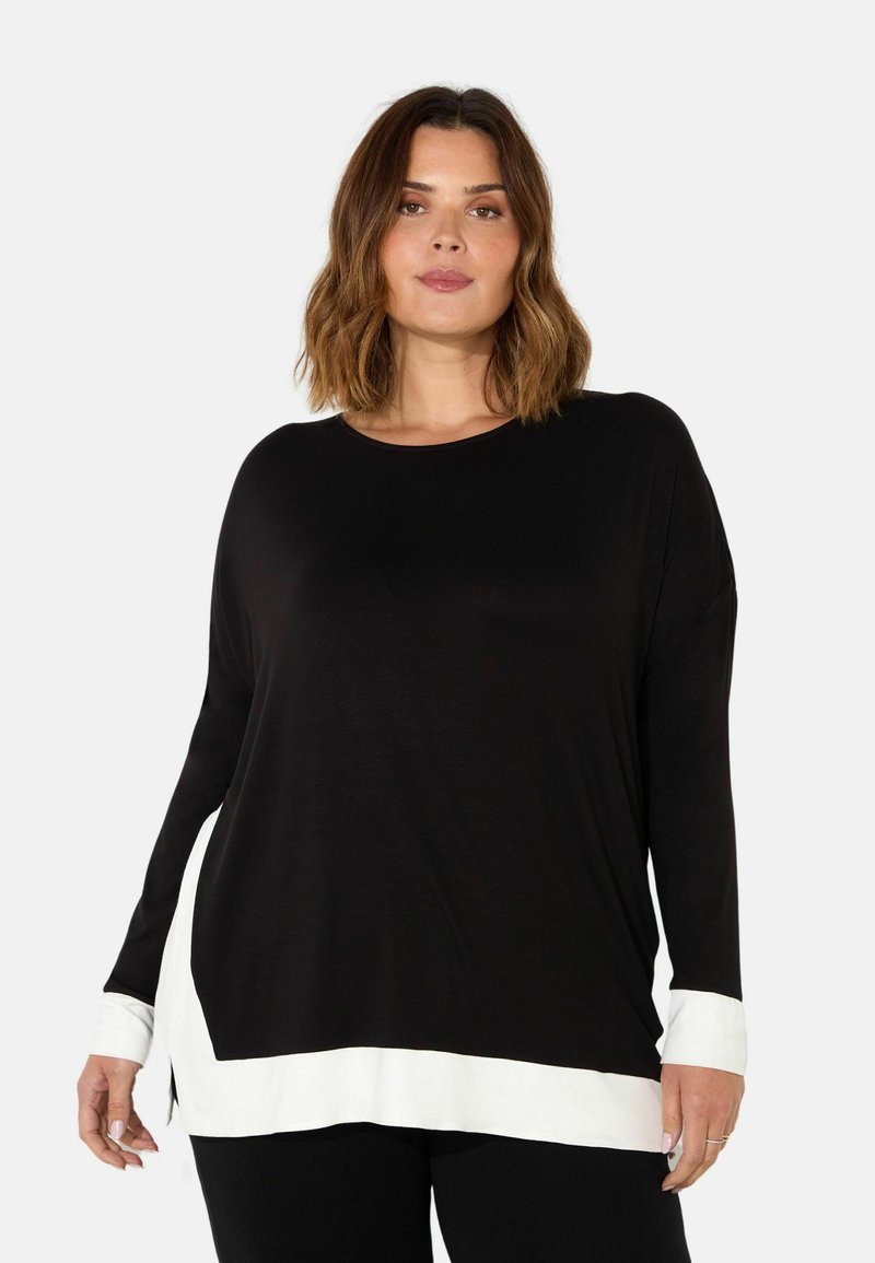 Black long-sleeve top with a rounded neckline and white hem accents. Soft fabric and relaxed fit with side slits. Classic color block design.