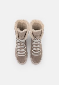 Botas de ante beige con forro de piel sintética y cordones grises. Presentan ojales de metal y un diseño de puntera redondeada. Superficie texturizada.