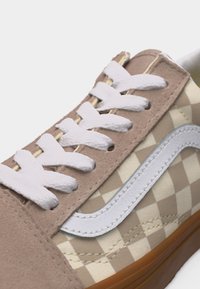 Baskets à carreaux beiges et crème avec lacets blancs, panneau œillet en suède beige, bande latérale blanche et semelle en caoutchouc marron.