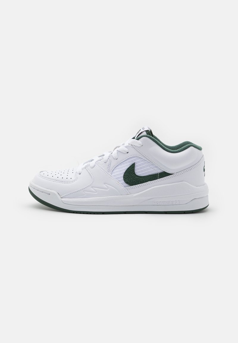 Baskets blanches basses avec un swoosh Nike vert foncé, une doublure intérieure verte, un bout perforé et une fermeture à lacets sur un fond blanc.