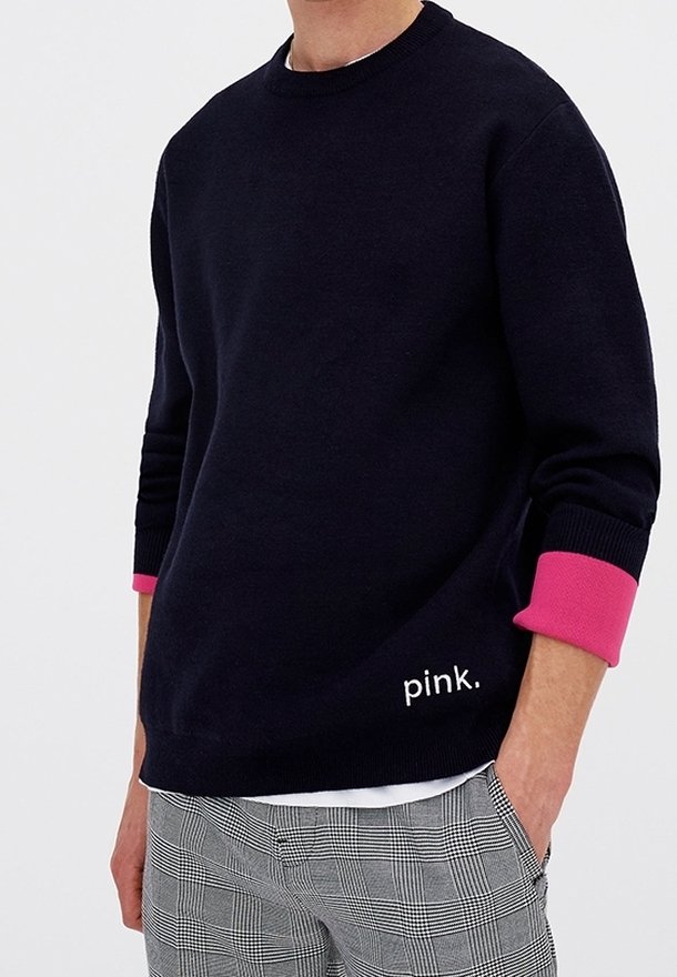 Maglione a collo rotondo navy con polsini rosa, con la parola "pink" ricamata in bianco. Materiale morbido, vestibilità comoda, abbinato a pantaloni a fantasia.