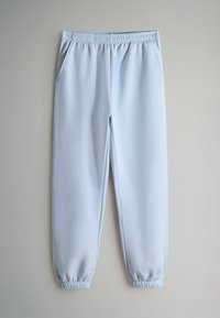 Svetlomodré tepláky vyrobené z mäkkého materiálu, s elastickým pásom a manžetami, dvoma bočnými vreckami a hladkým povrchom.