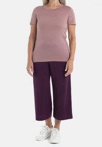 Kortärmad mauve t-shirt i kombination med löst sittande, knälånga lila culotter och vita sneakers. Enkelt, mjukt tyg med avslappnad passform.